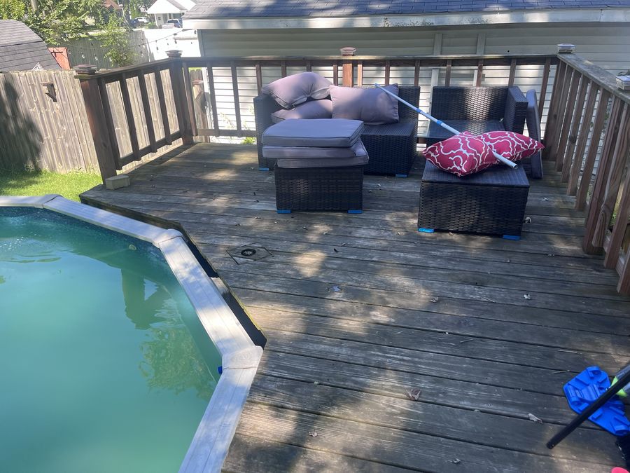 Pool deck before pressure washing — weathered grey boards